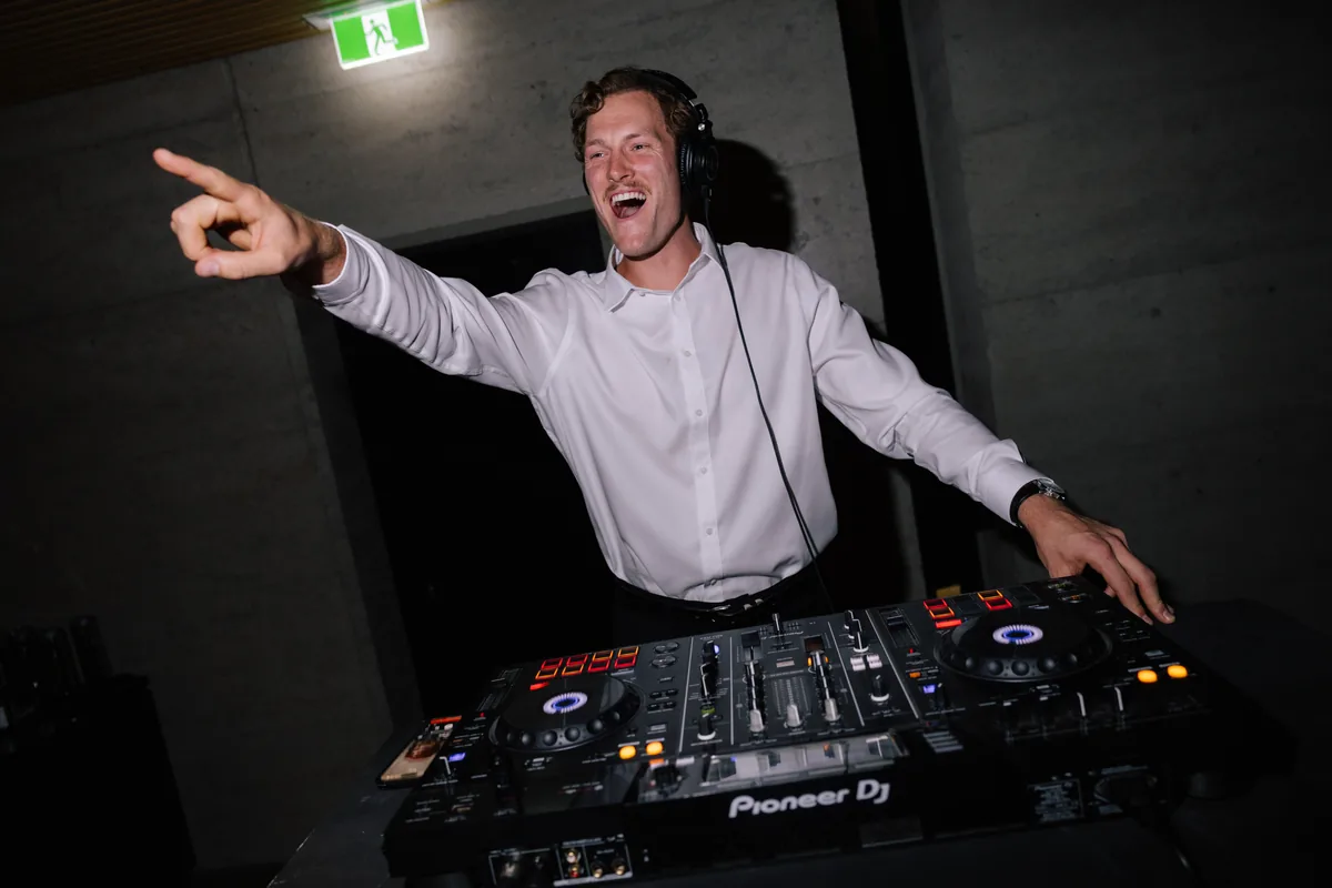 Jem Pryse behind the decks with one arm in the air