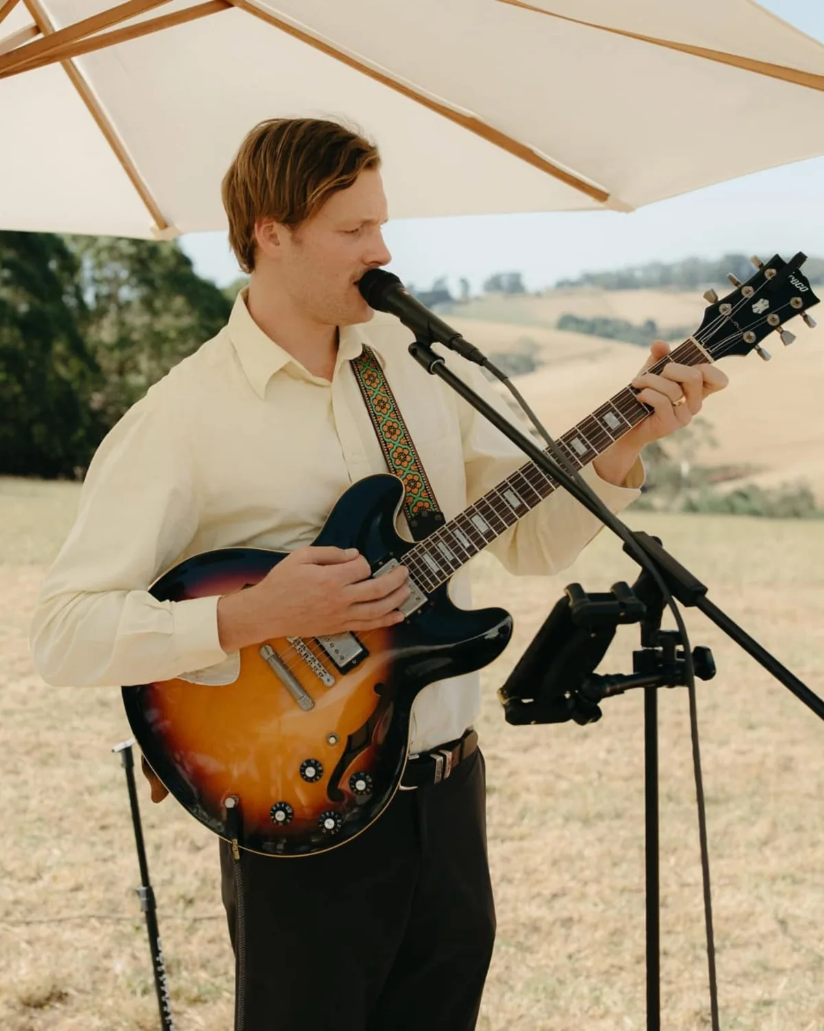 Jem Pryse singing and playing electric guitar outdoors at a wedding